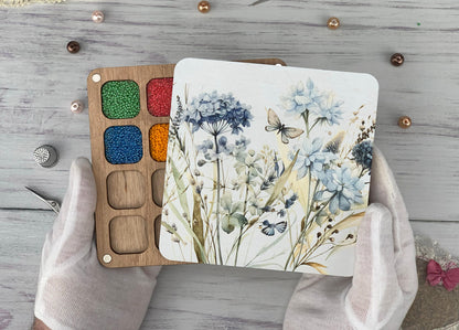 a person&#39;s hands holding a paint palette and a painting board