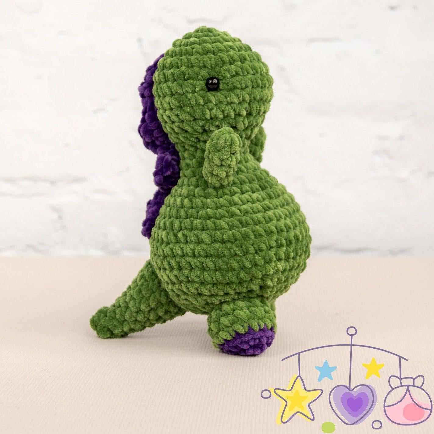 a crocheted green and purple dinosaur sitting on a table