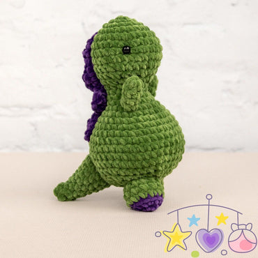 a crocheted green and purple dinosaur sitting on a table