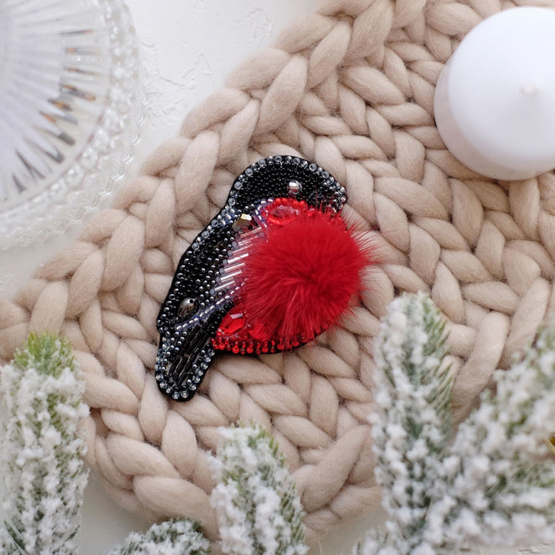 a red and black brooch sitting on top of a knitted blanket