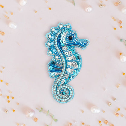 a blue seahorse brooch sitting on top of a white surface