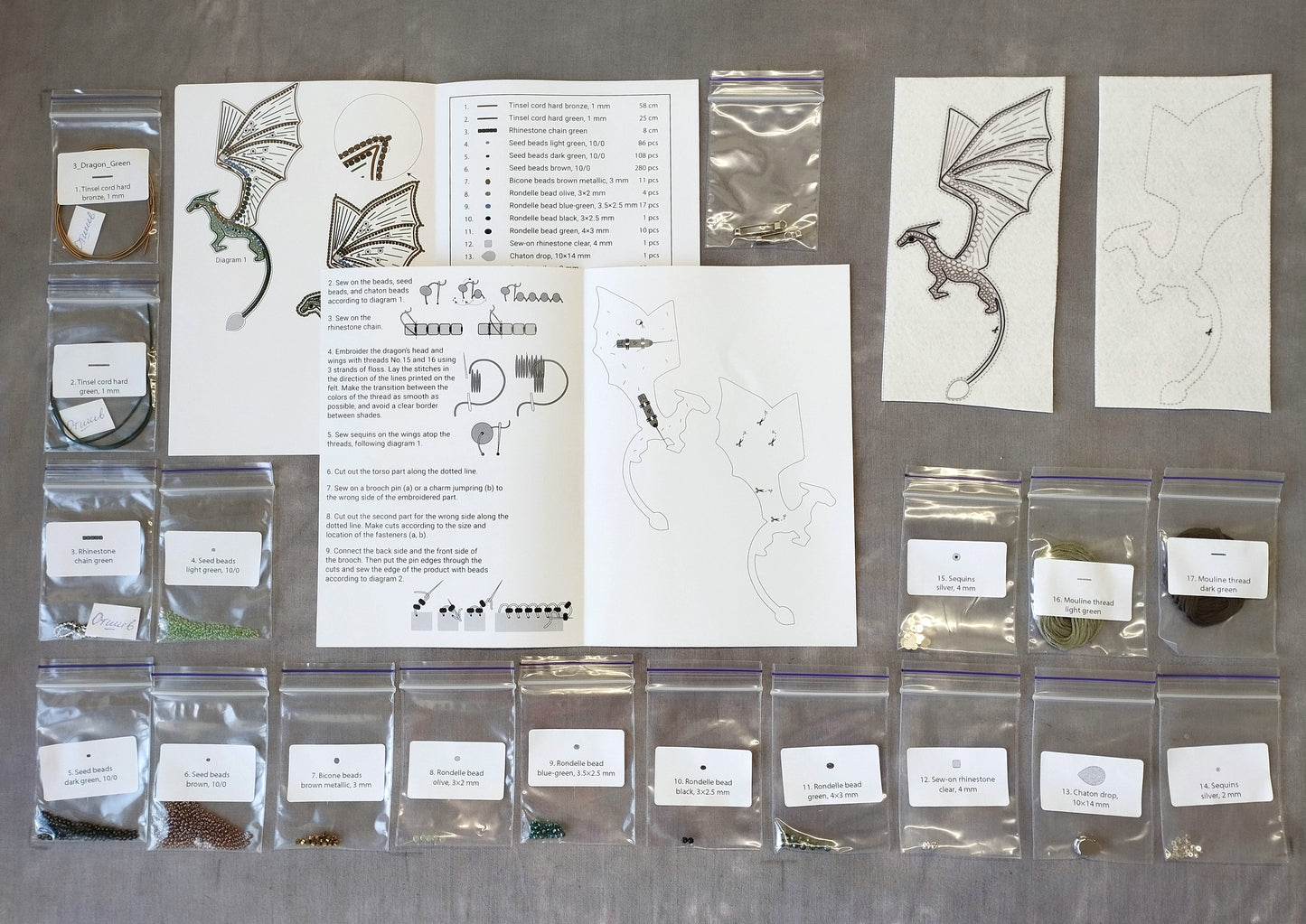 various craft supplies and materials, including bags of beads, a book with instructions, and several printed images of dragon and cat designs.