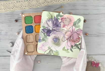 a person&#39;s hands holding a palette of watercolors