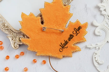 a close up of a leaf shaped brooch with a name on it