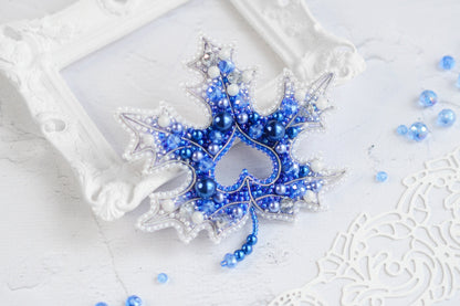 a blue and white beaded snowflake in a frame