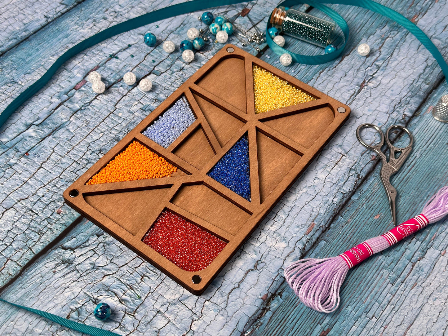 a wooden tray with beads and a pair of scissors