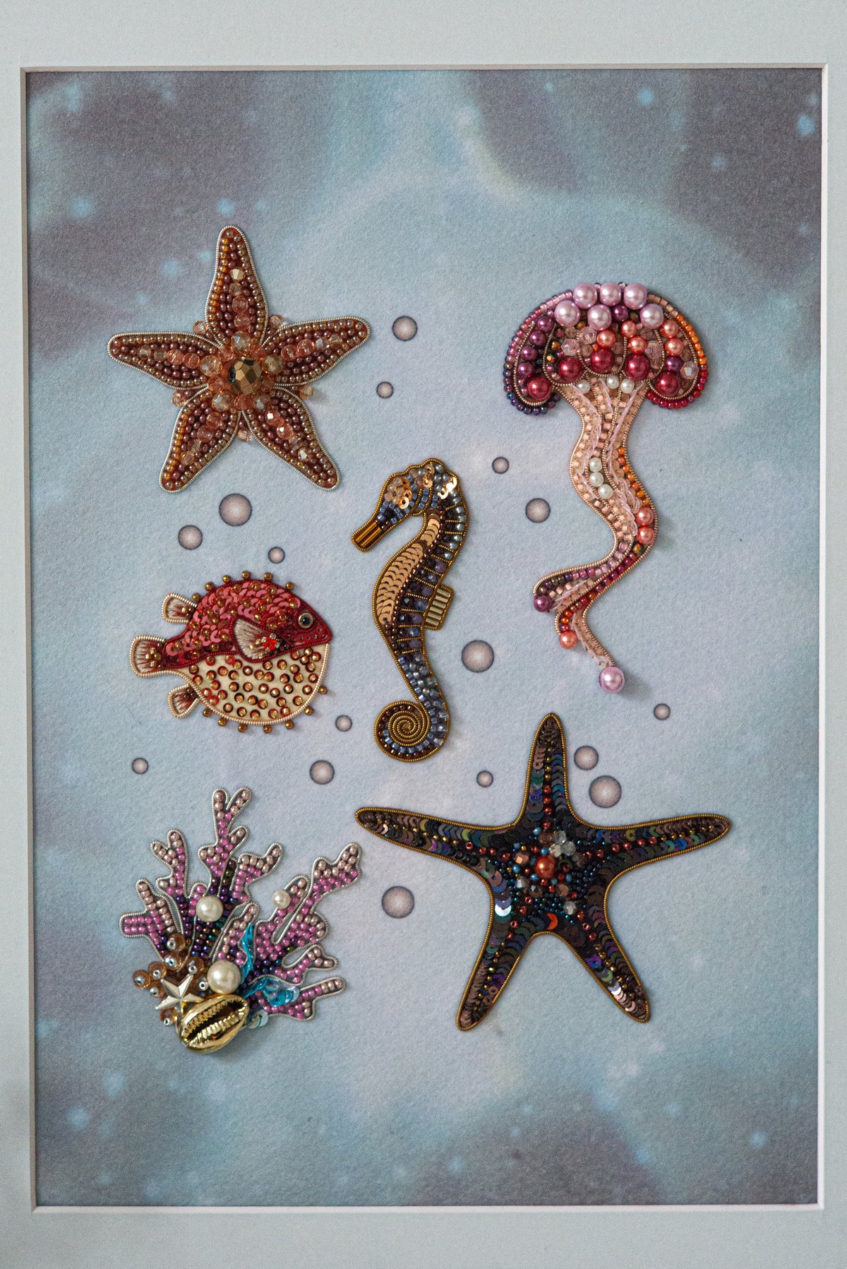 a collection of six decorative sea-themed objects, including a starfish, a jellyfish, a seahorse, a pearlfish, a star, and a coral.