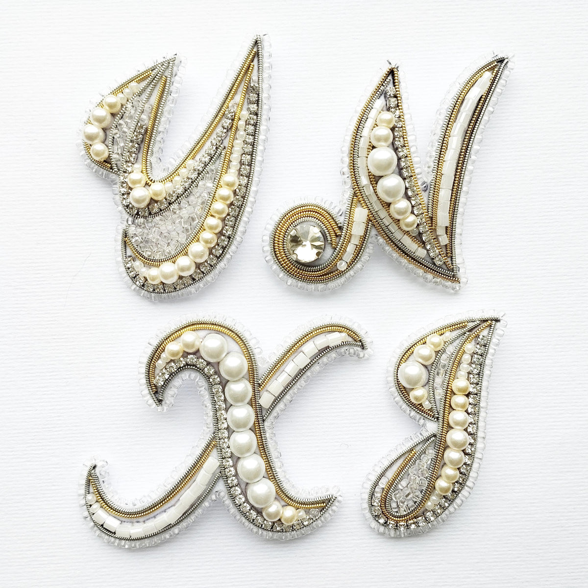 a collection of ornate, decorative elements that appear to be made of pearls, beads, and other embellishments. The elements are arranged in a way that they form the letters of the alphabet, creating a visually appealing and intricate design.