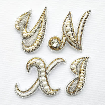 a collection of ornate, decorative elements that appear to be made of pearls, beads, and other embellishments. The elements are arranged in a way that they form the letters of the alphabet, creating a visually appealing and intricate design.
