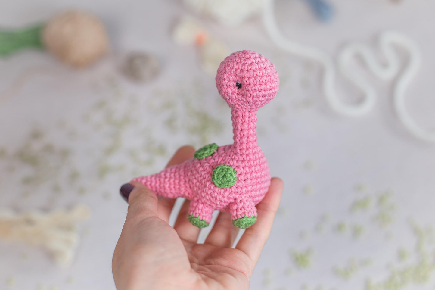 a pink crocheted toy of a pink dinosaur