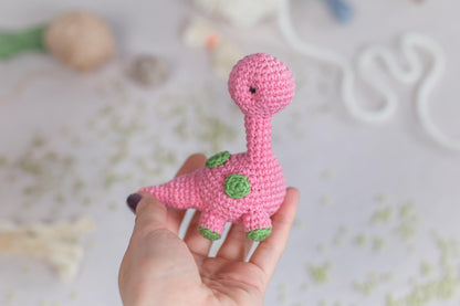 a pink crocheted toy of a pink dinosaur