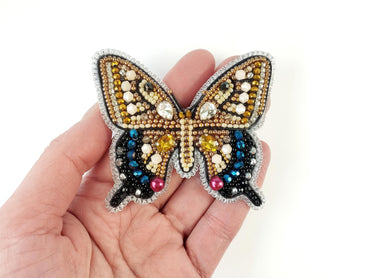 a hand holding a butterfly brooch in it&#39;s left hand