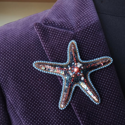 A close-up image of a purple fabric with a starfish-shaped brooch or pin adorned with colorful beads and sequins.