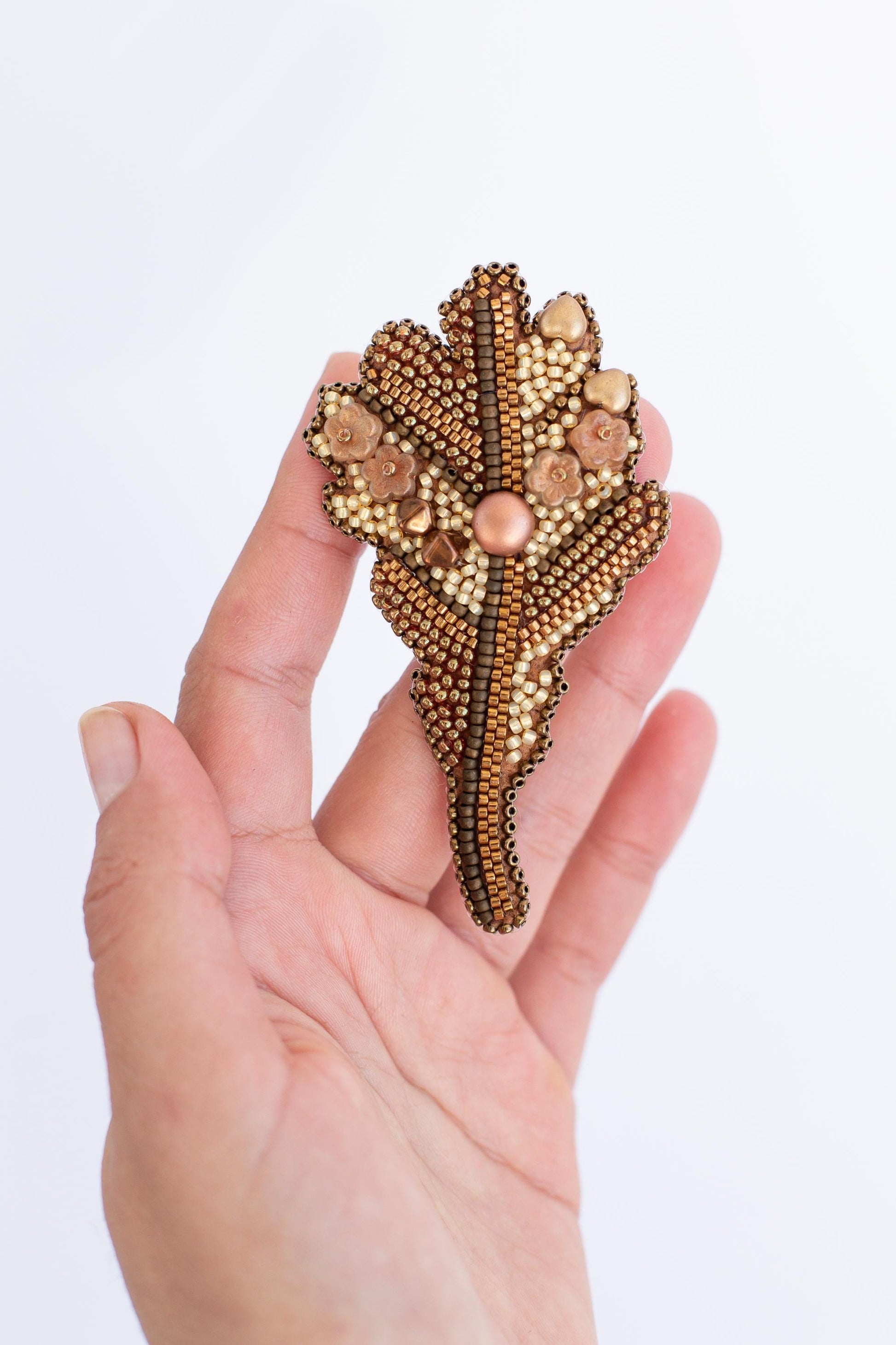 a hand is holding a brooch with beads