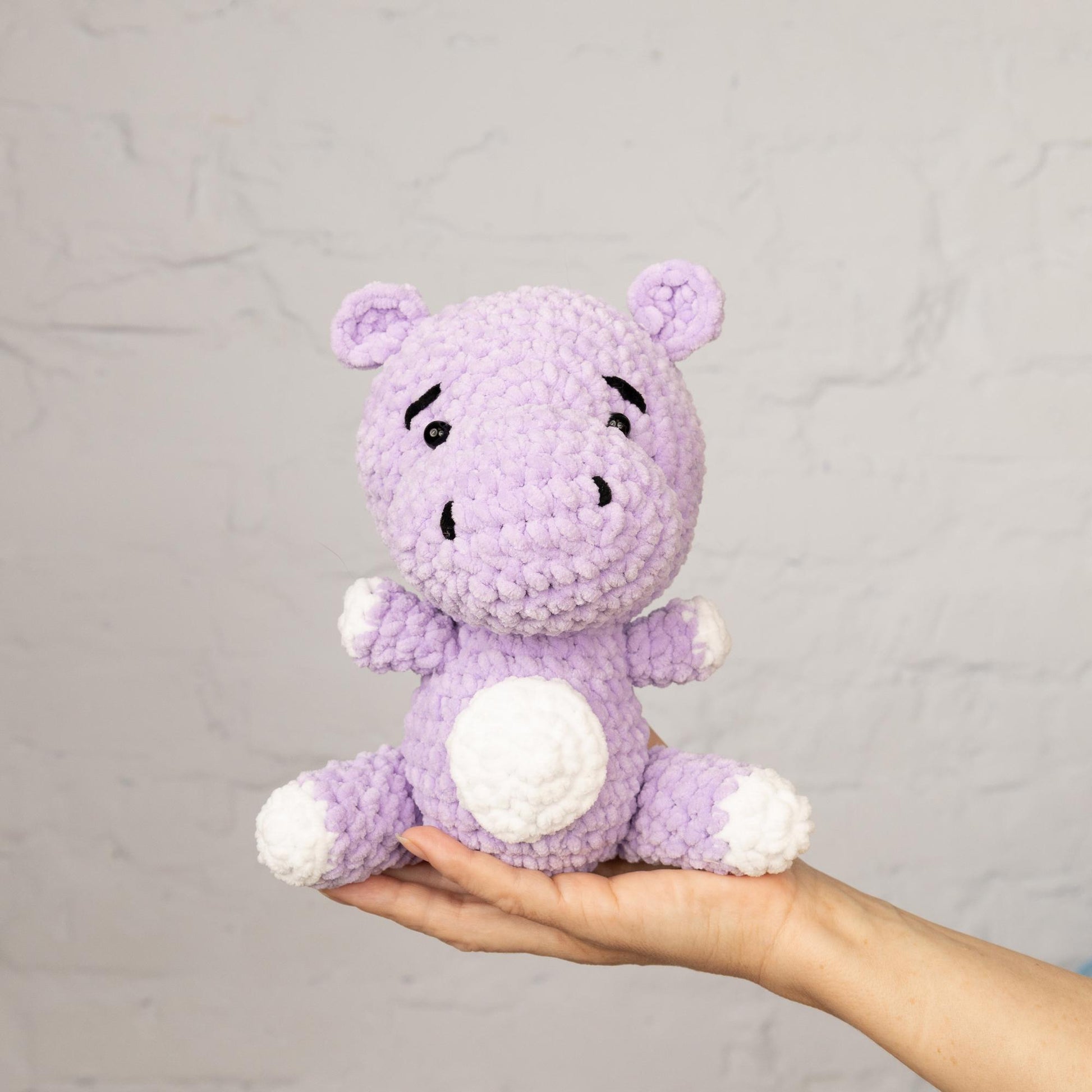 a hand holding a purple crocheted stuffed animal