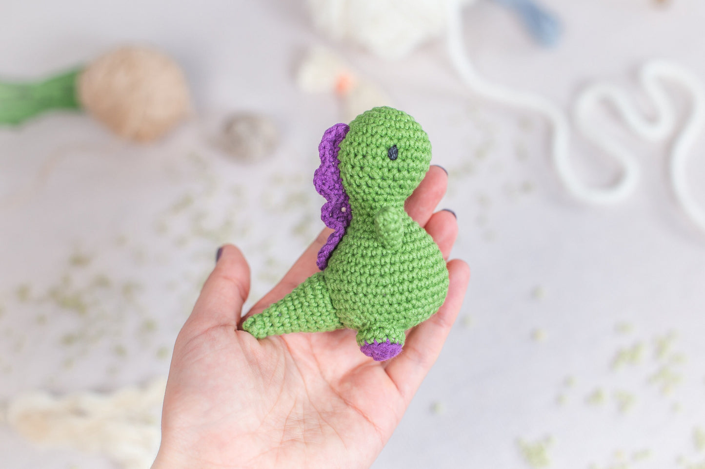 a hand holding a small green crocheted toy