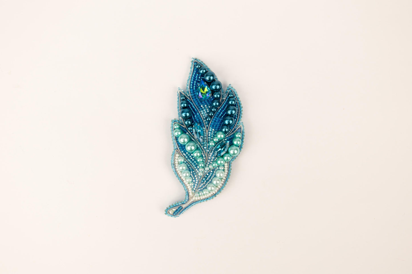 a brooch with a blue and green feather on it