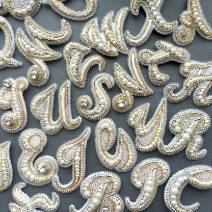 a collection of ornate, bejeweled letter-shaped objects arranged on a dark background.