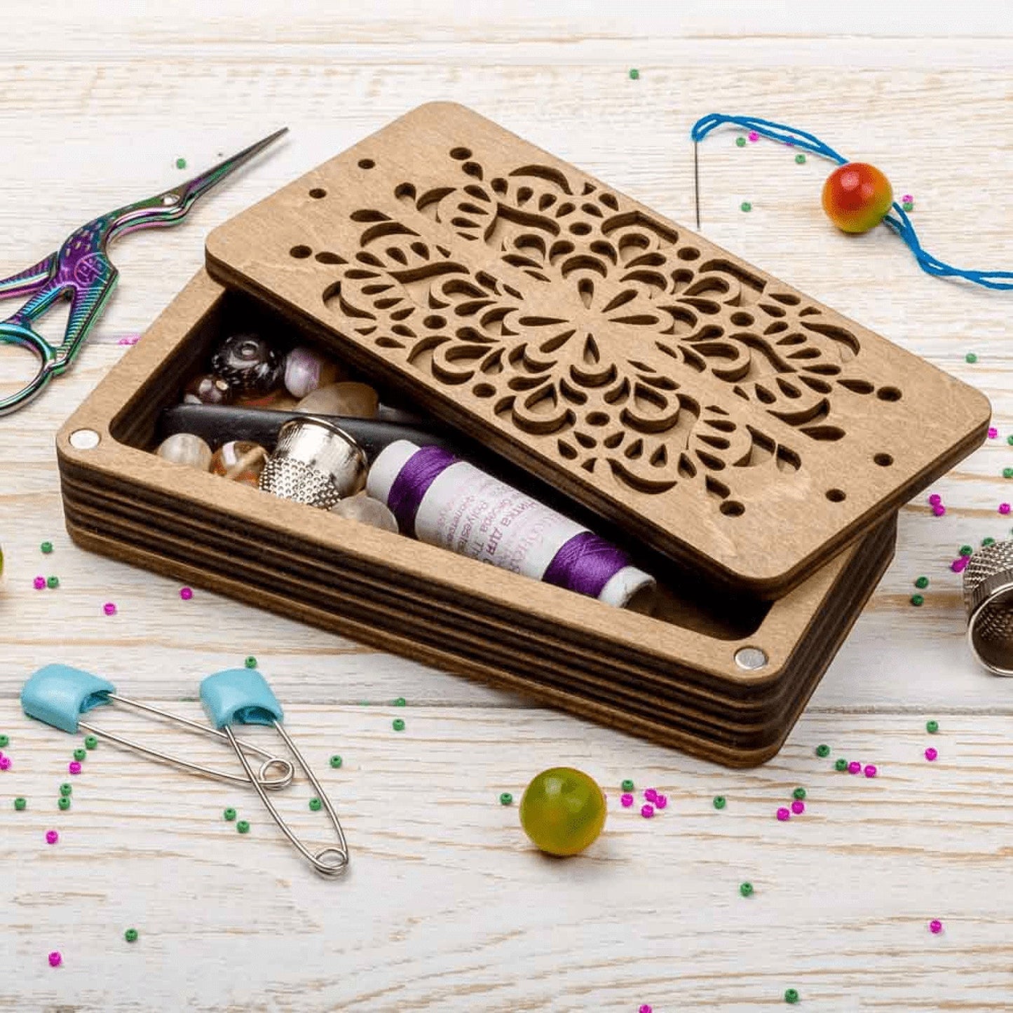 a wooden box filled with sewing supplies on top of a table