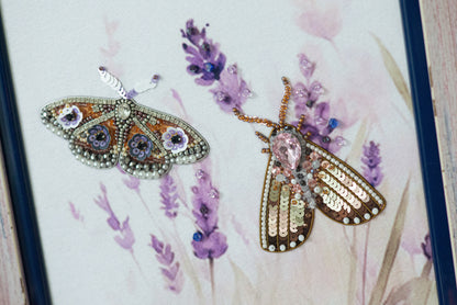 two intricately designed butterflies, one with a brown and black color scheme and the other with a pink and gold color scheme, set against a background of purple flowers.