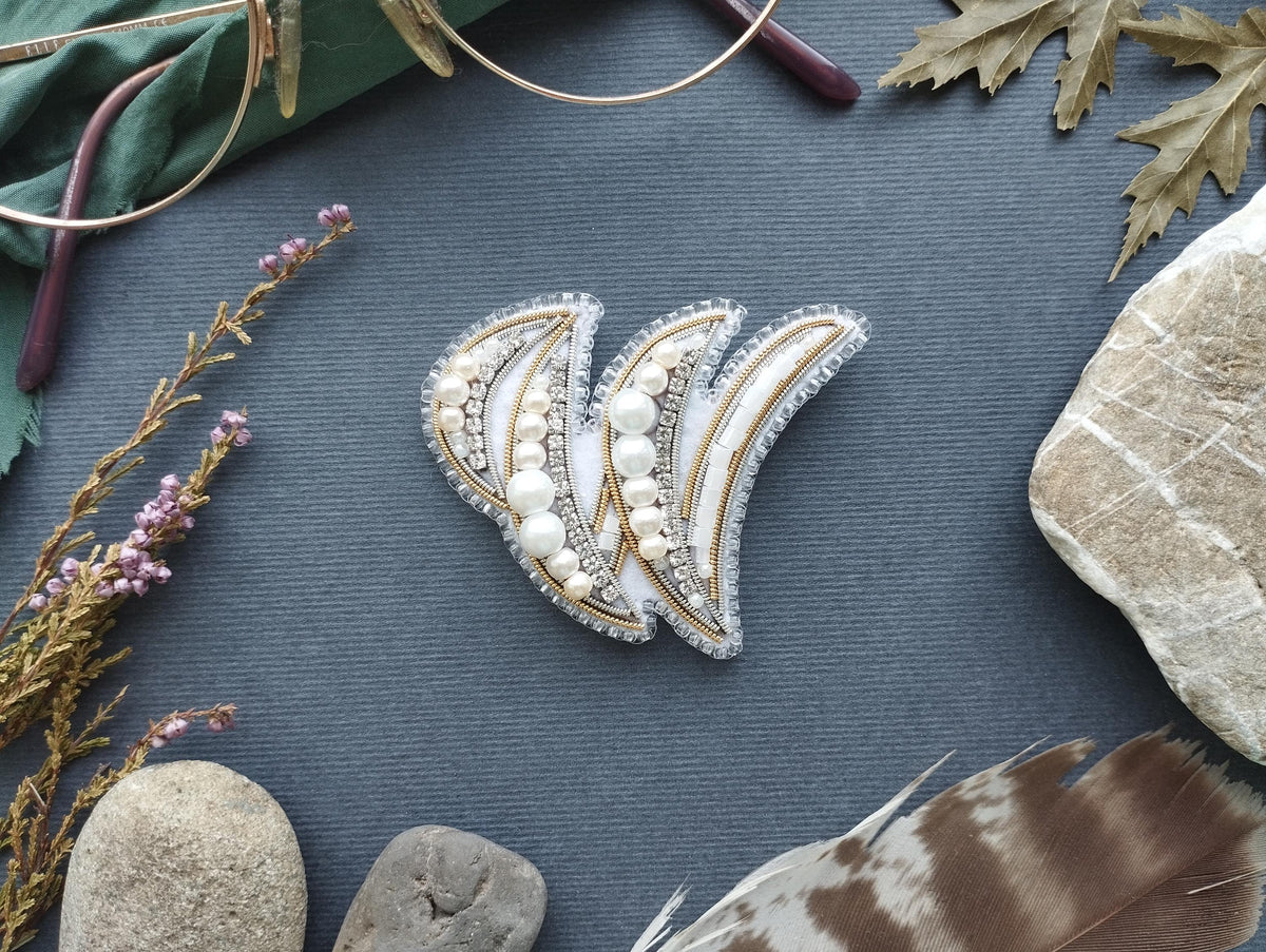 a close-up view of a decorative piece with a floral design, placed on a blue surface surrounded by various natural elements such as rocks, feathers, and flowers.