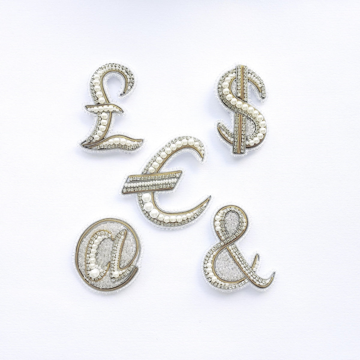 five ornate, beaded, and crystal-like objects arranged in a way that spells out the words 'L', 'S', 'E', 'C', and 'A' on a white background.