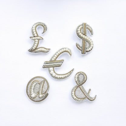 five ornate, beaded, and crystal-like objects arranged in a way that spells out the words 'L', 'S', 'E', 'C', and 'A' on a white background.