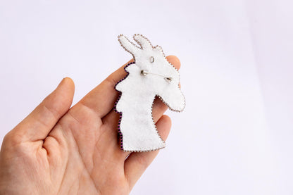 a person is holding a white brooch with a giraffe design on it
