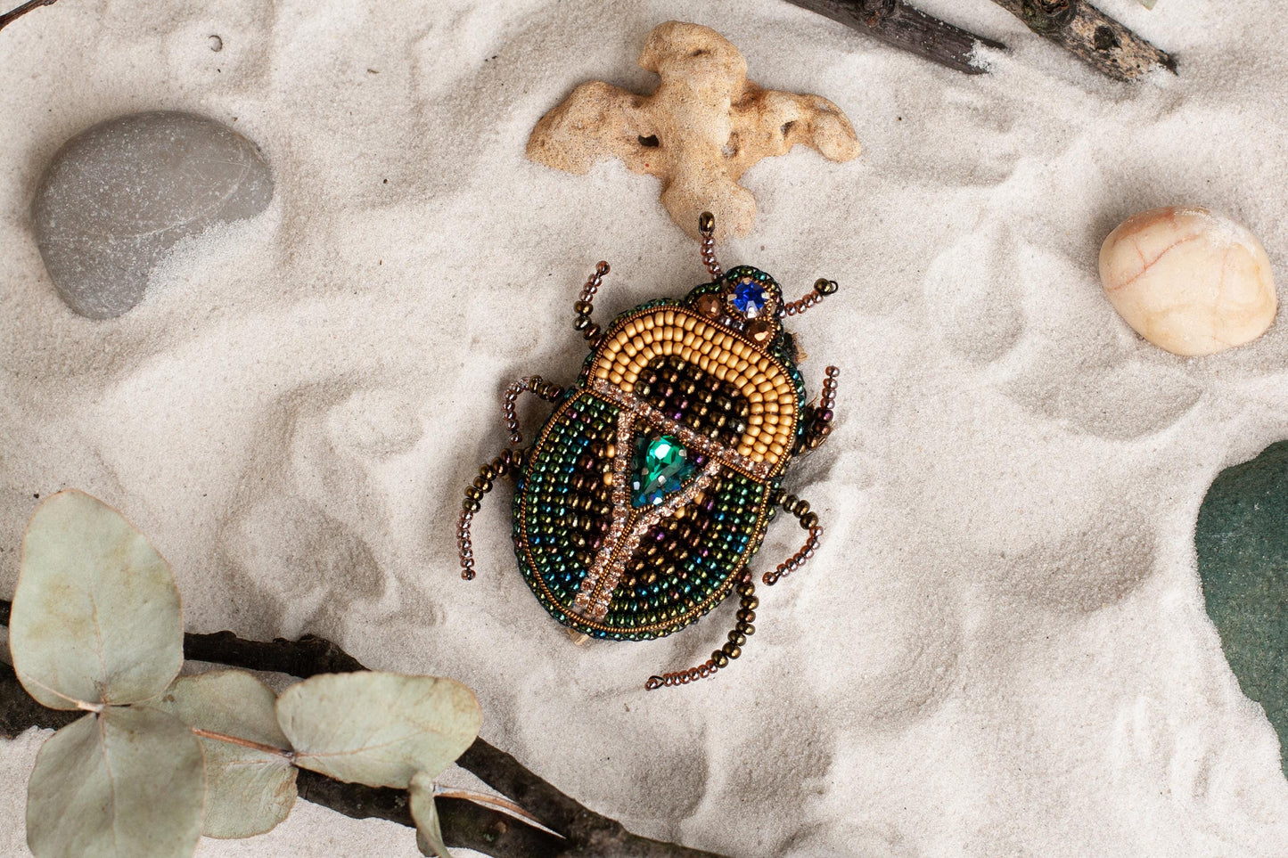 a beetle is sitting on the sand next to a plant