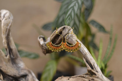 a pair of earrings sitting on top of a piece of wood