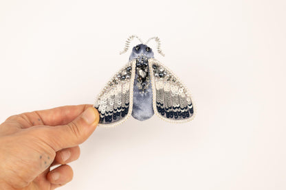 a hand holding a tiny blue and white insect