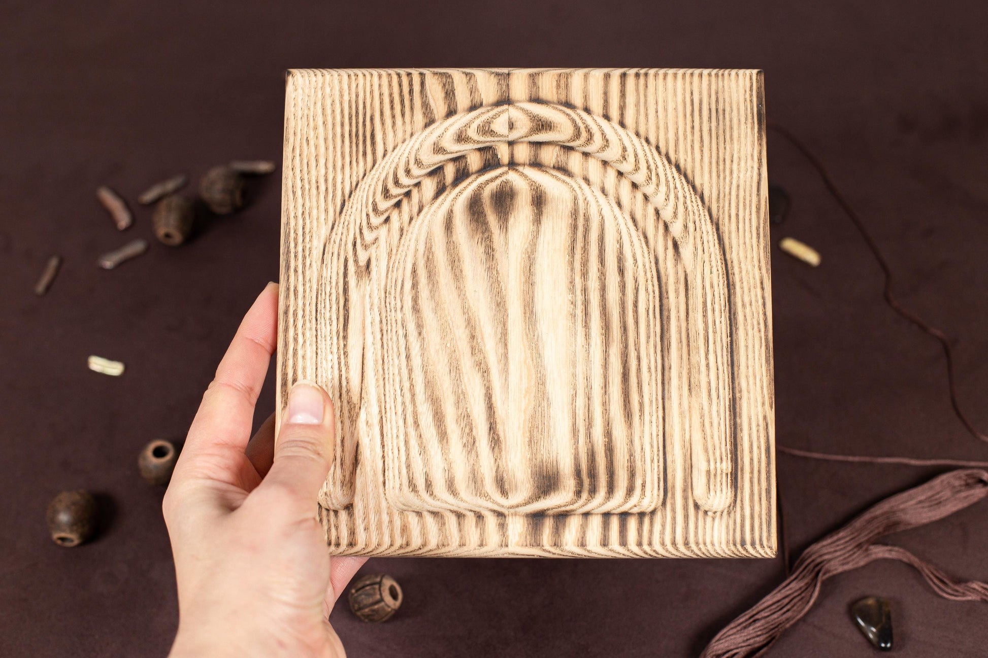 a hand holding a wooden block with a design on it