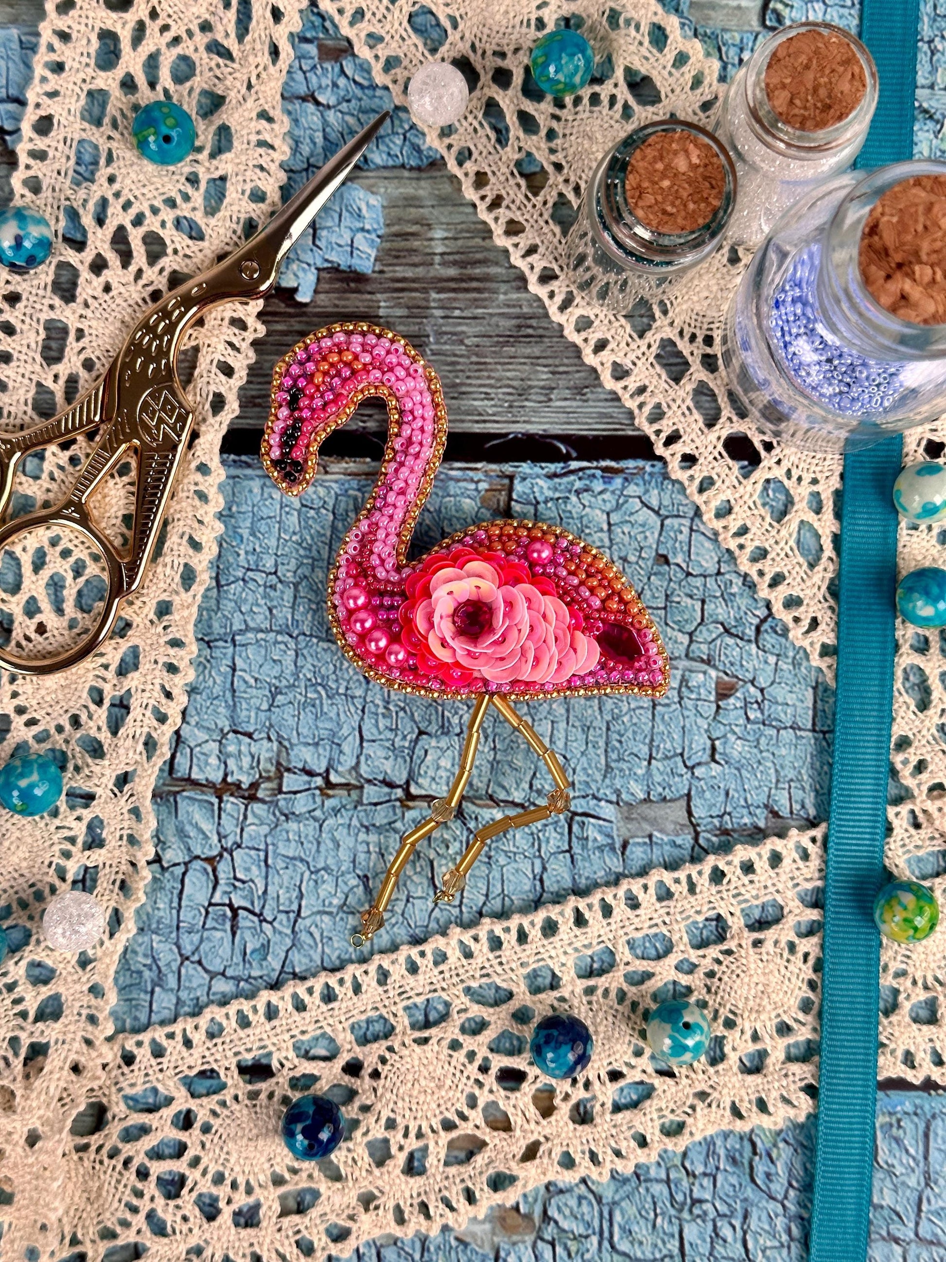 a pink flamingo pin sitting on top of a table next to a pair of