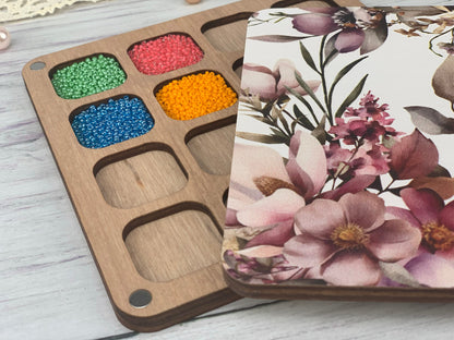 a wooden tray with beads in it next to a box of beads
