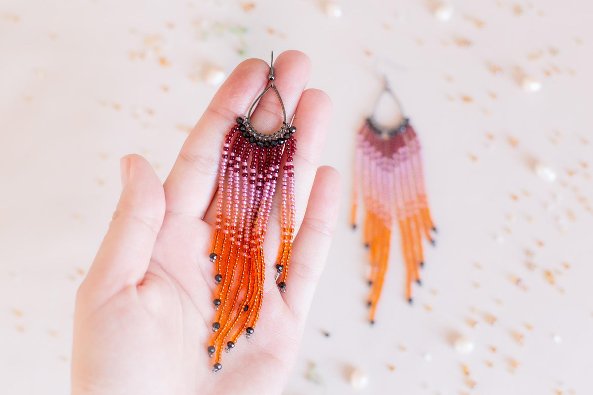 a hand holding a pair of beaded earrings