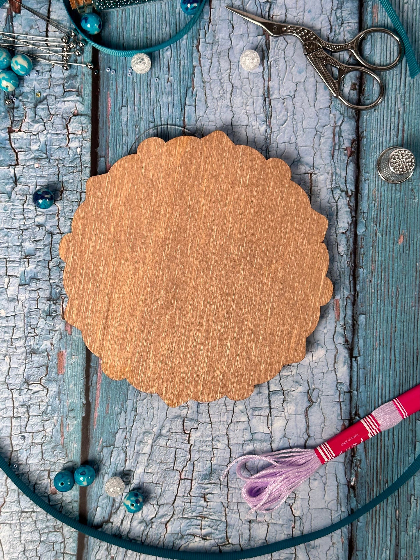 a wooden circle surrounded by scissors and beads