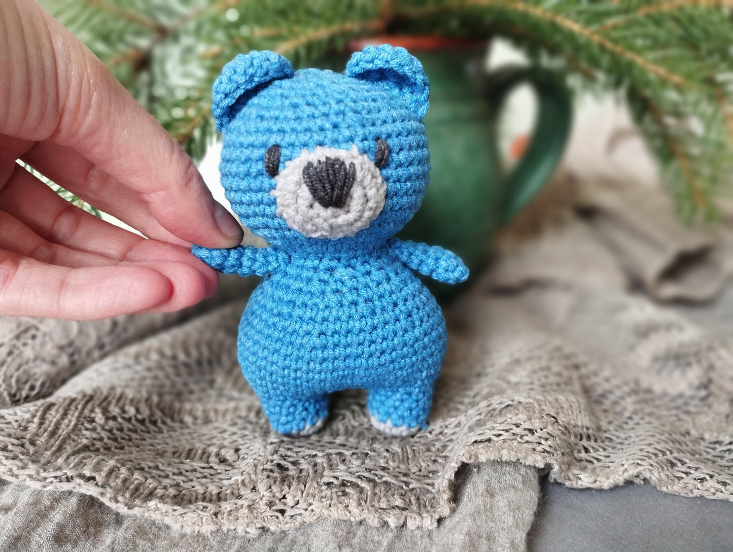 a crocheted blue teddy bear sitting on top of a table