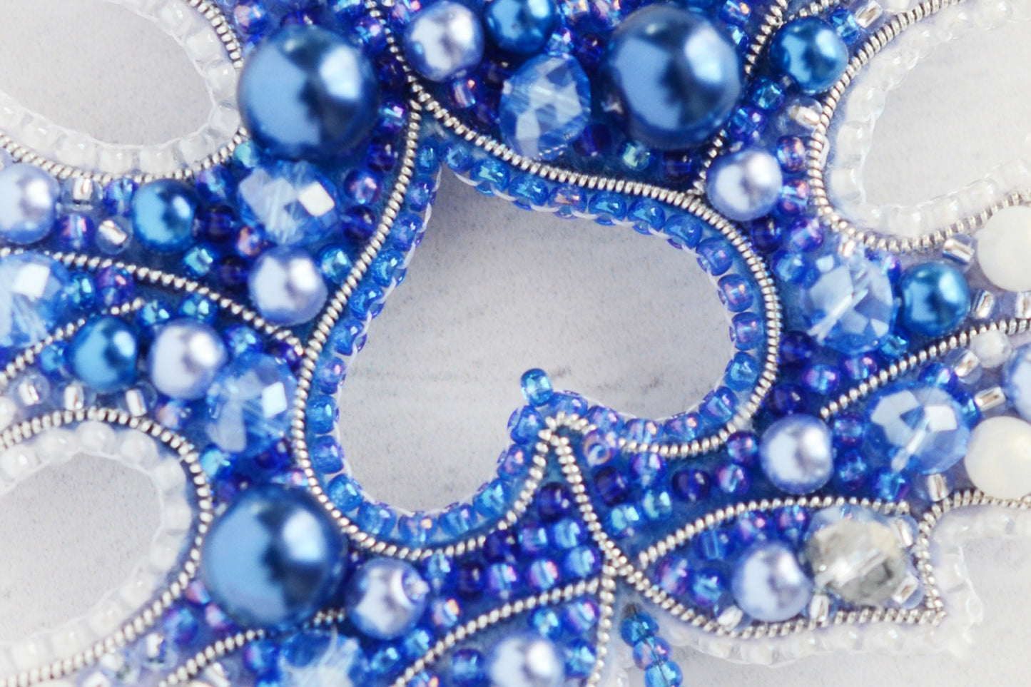 a close up of a blue and white beaded mask