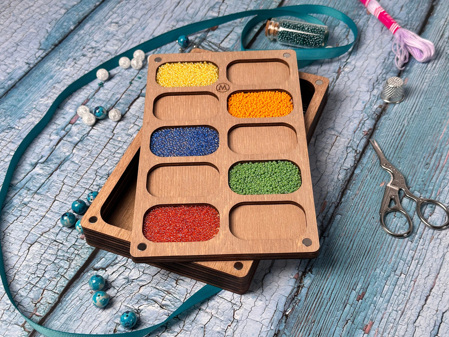 a wooden tray with different colored beads and a pair of scissors