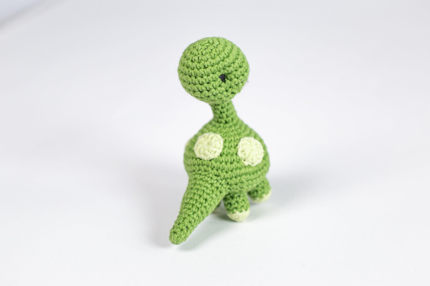 a crocheted toy of a green dinosaur