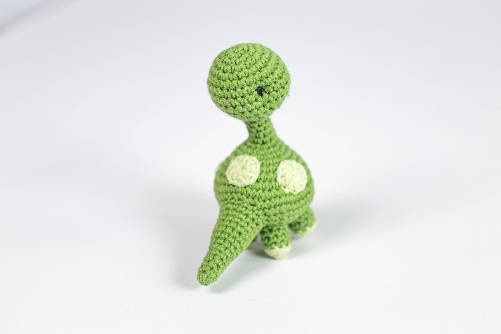 a crocheted toy of a green dinosaur
