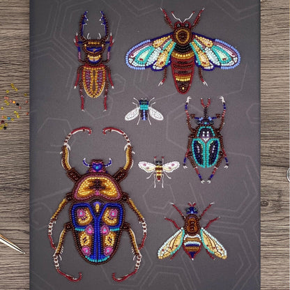 a collection of six intricately designed, colorful, and detailed insects, including a large dragonfly, a bee, a butterfly, a ladybug, a praying mantis, and a grasshopper, all crafted from beads.