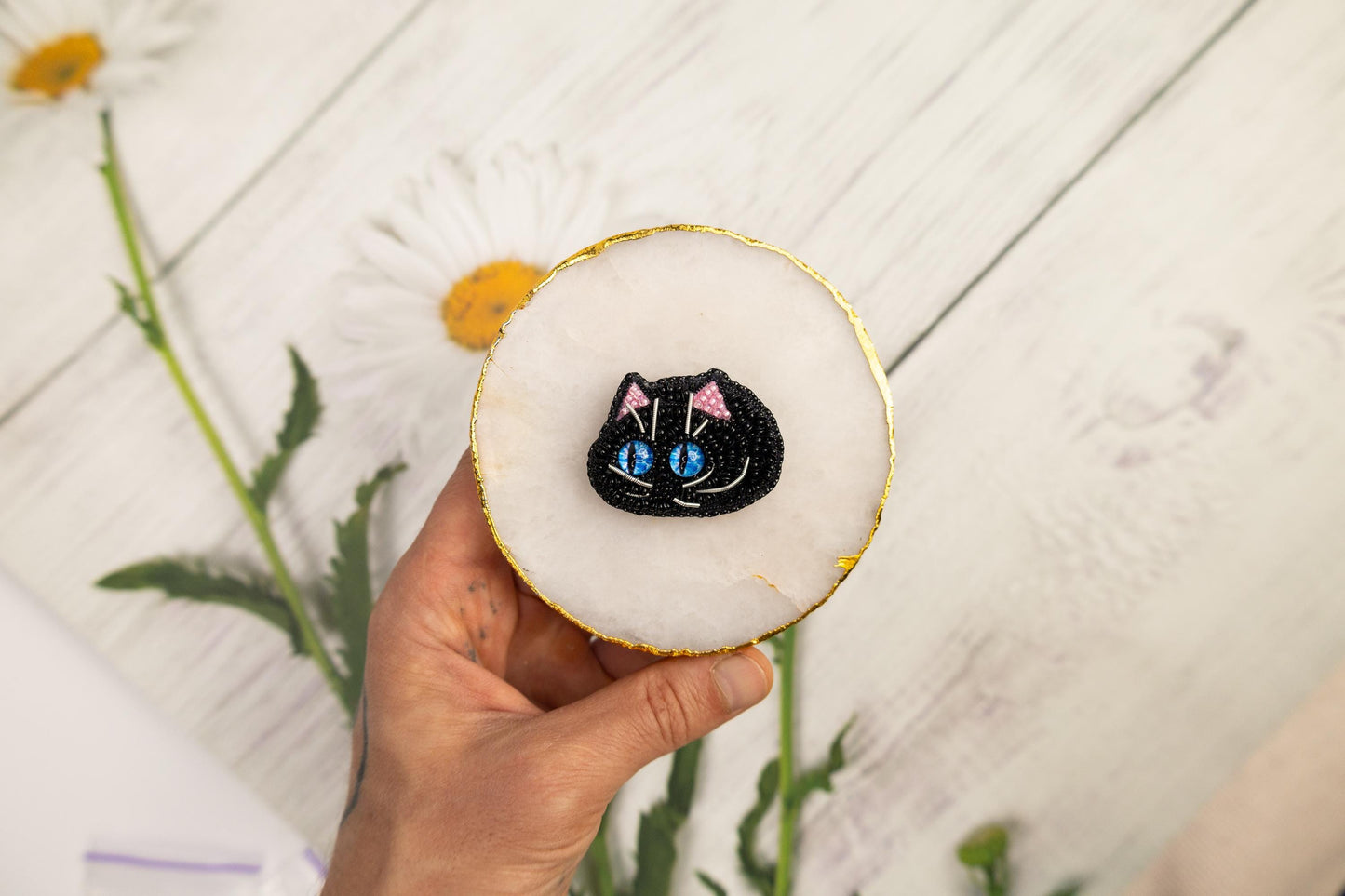 a person holding a cat brooch in their hand