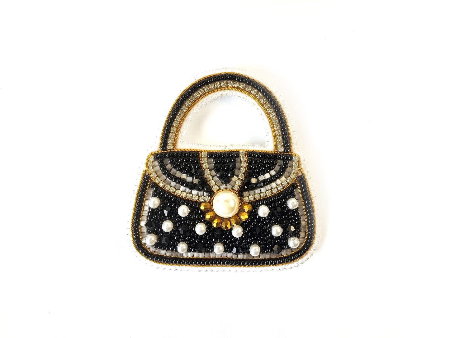 A handbag made of black beads and white pearls, with a gold-colored clasp and a large pearl at the center.