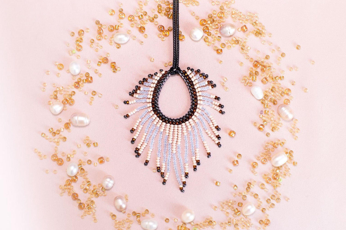 a beaded necklace with a large, open pendant surrounded by scattered pearls and beads in various shades of gold and white.