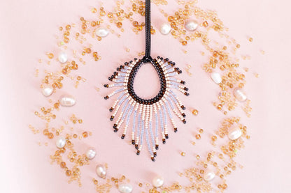 a beaded necklace with a large, open pendant surrounded by scattered pearls and beads in various shades of gold and white.