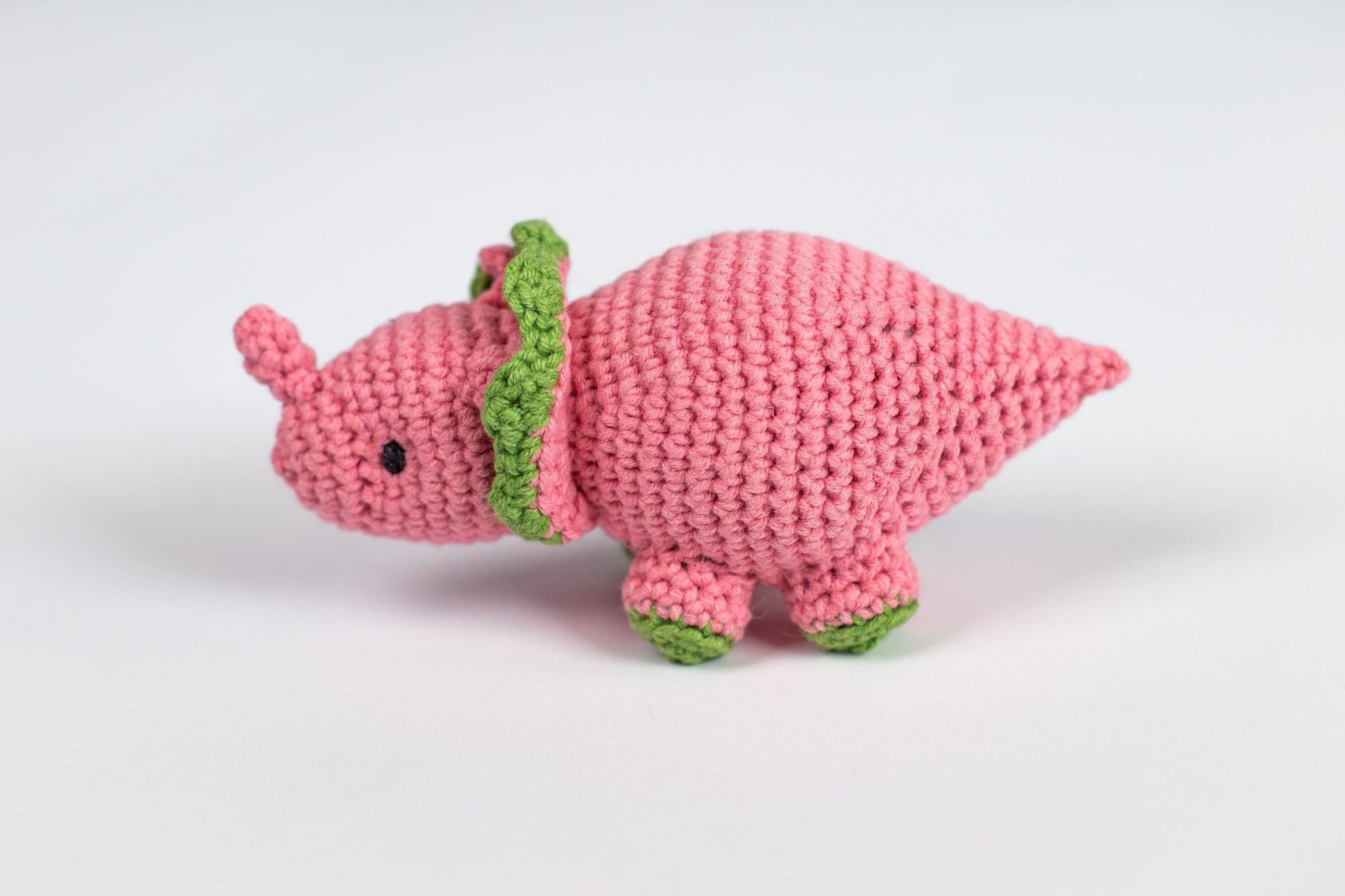 a pink crocheted stuffed animal with a green stem