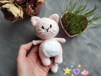 a crocheted cat next to a vase of flowers
