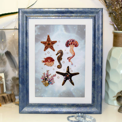 A framed collage of various sea creatures, including a starfish, a jellyfish, a seahorse, a fish, and a coral, is displayed on a shelf.