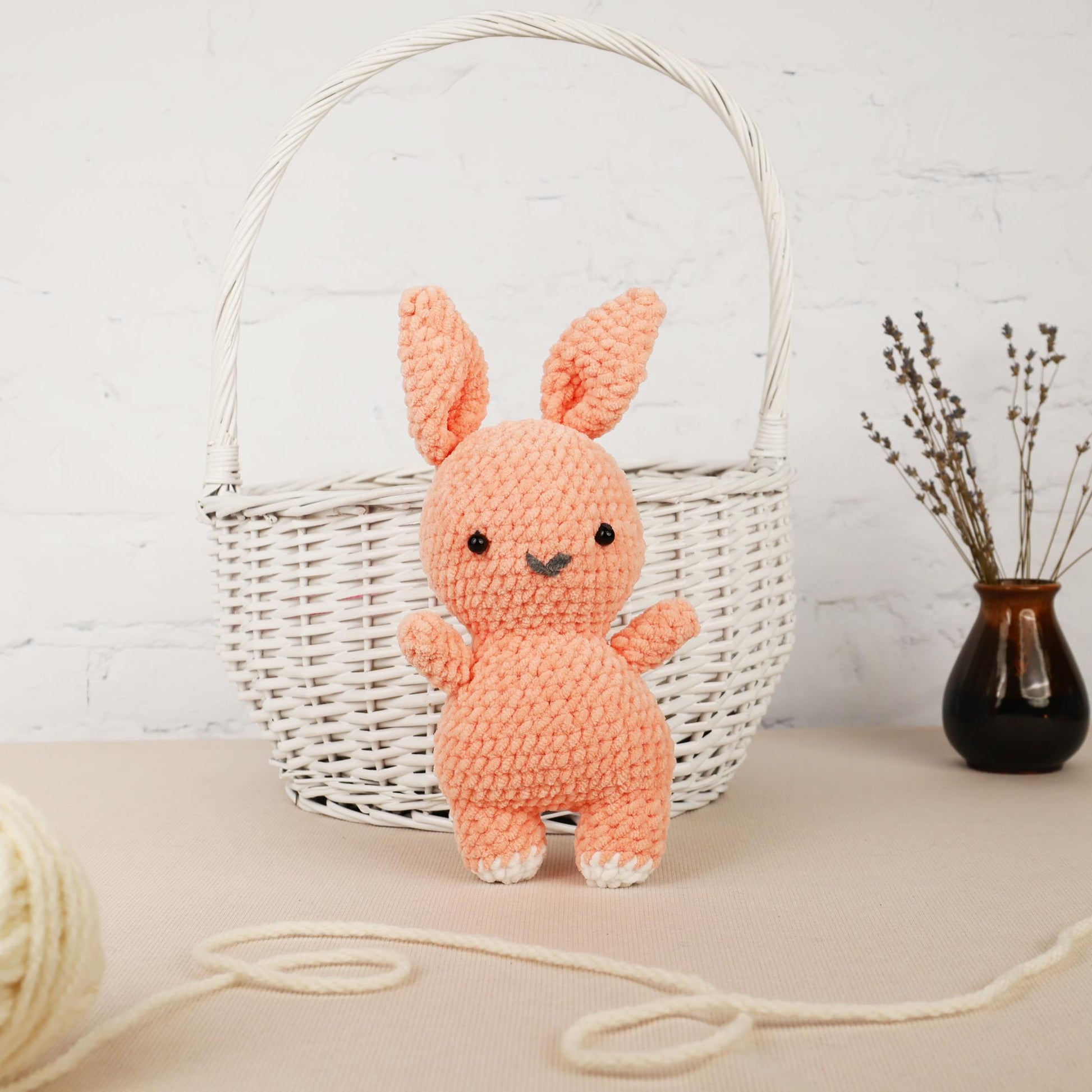 a crocheted bunny sitting in front of a basket